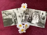 Image shows black and white photographs sitting on a surface with flowers. 