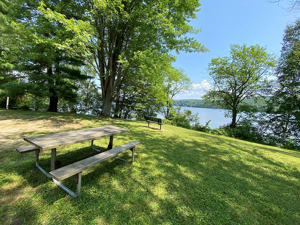 Image shows Lake of Bays at Dorset Parkette with picnic table in the foreground.