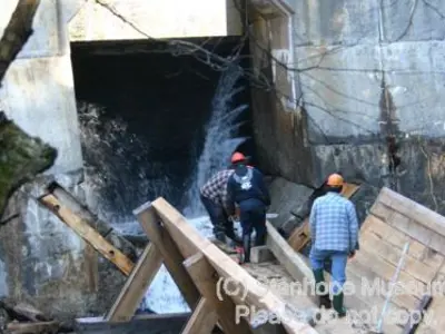 Image shows members of the construction team walking on the largely completed log chute. 