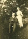 Image shows a black and white photo of an elderly couple outdoors. 