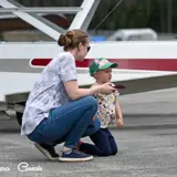 Image shows a parent and child with aircraft in the background. 