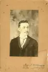 Image shows a black and white portrait of a man dressed in suit and tie. 