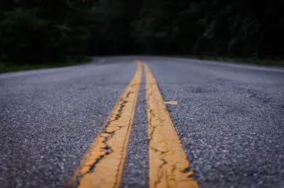 Image shows yellow centre lines on a paved road. 