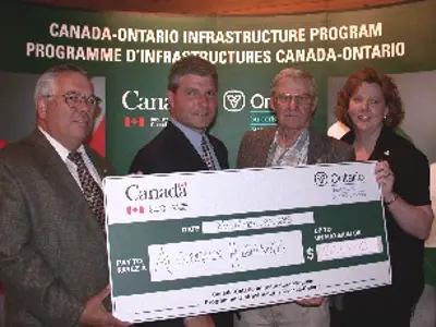 Image shows a group of people holding a large novelty cheque. 