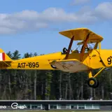 Image shows a yellow propeller plane in flight. 