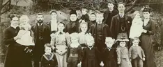 Image shows a black and white photo of a family dressed in old-fashioned clothing. 