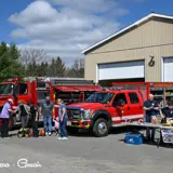 Image shows a crowd looking at Algonquin Highlands Fire Services trucks and equipment. 