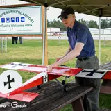 Image shows a man with a model airplane. 