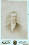 Image shows faded portrait of a man in a suit. 