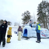 Image shows children lined up at an inflatable slide featuring a polar bear. 