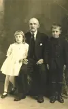 Image shows what appears to be a family portrait with a seated man between two standing children. 