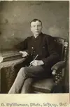 Image shows portrait of a well-dressed man, seated. 