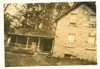 Image shows a black and white image of a stone farmhouse. 